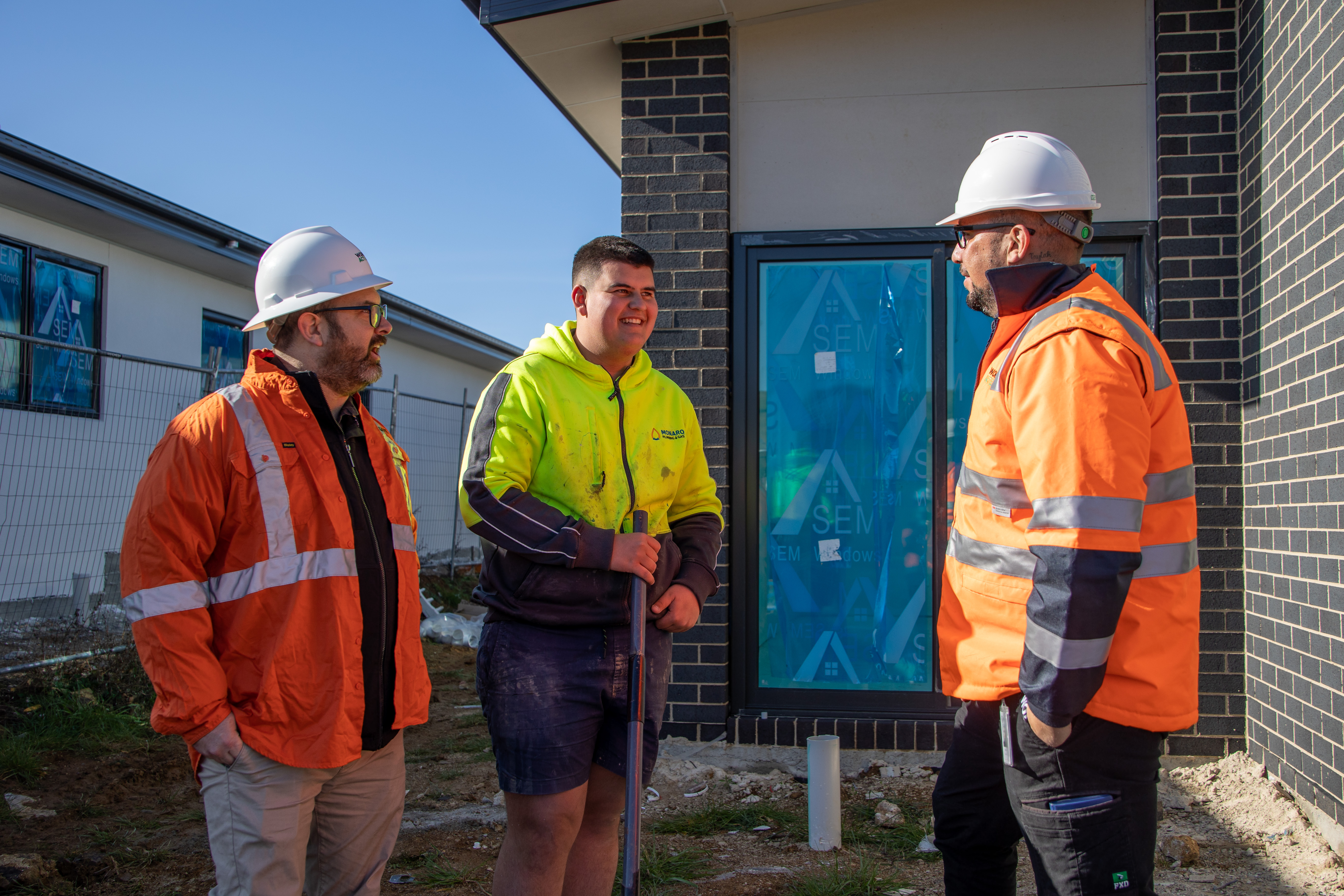 An apprentice talks to two WorkSafe ACT inspectors, the group are all smiling